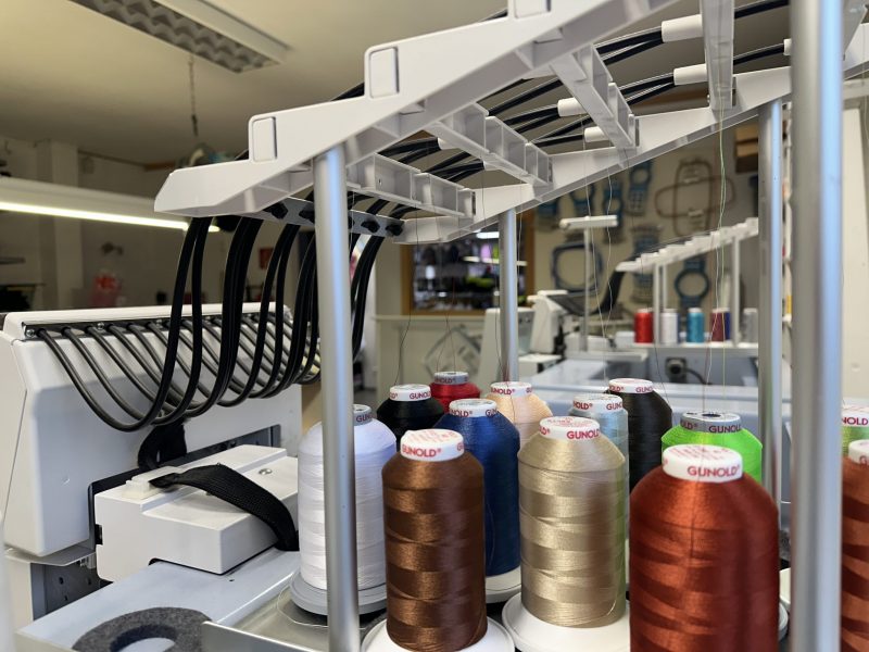 Nahaufnahme einer professionellen Stickmaschine mit Gunold-Stickgarn in verschiedenen Farben, bereit für die Veredelung von Textilien.