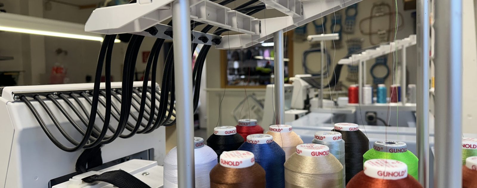 Nahaufnahme einer professionellen Stickmaschine mit Gunold-Stickgarn in verschiedenen Farben, bereit für die Veredelung von Textilien.