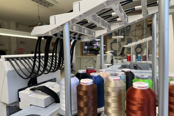 Nahaufnahme einer professionellen Stickmaschine mit Gunold-Stickgarn in verschiedenen Farben, bereit für die Veredelung von Textilien.