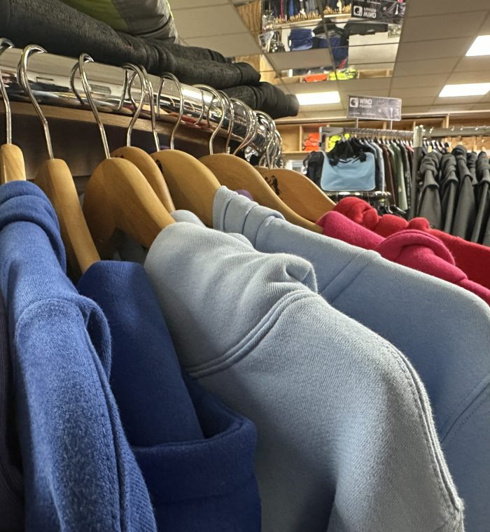 Hoodies in verschiedenen Farben, darunter Blau, Hellblau und Rot, hängen auf Holzbügeln im Laden von MP Berufsbekleidung.